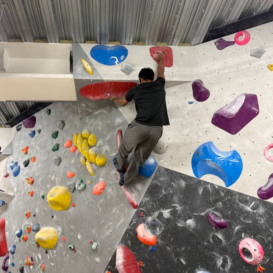 Bouldering a steep wall, reaching for a red hold